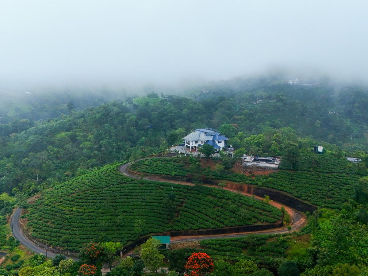 Aerial view of Zen Garden Vagamon on its hilltop, ringed by a winding road through tea gardens