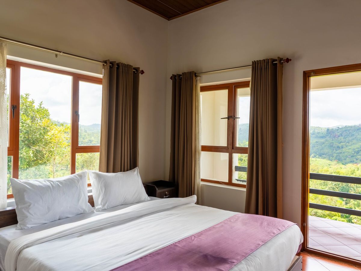 Bedroom with a king bed and floor-to-ceiling windows facing the valley at Zen Garden Vagamon